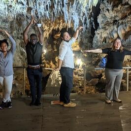 Fellows in a cave spelling out the letters to OIST with their bodies